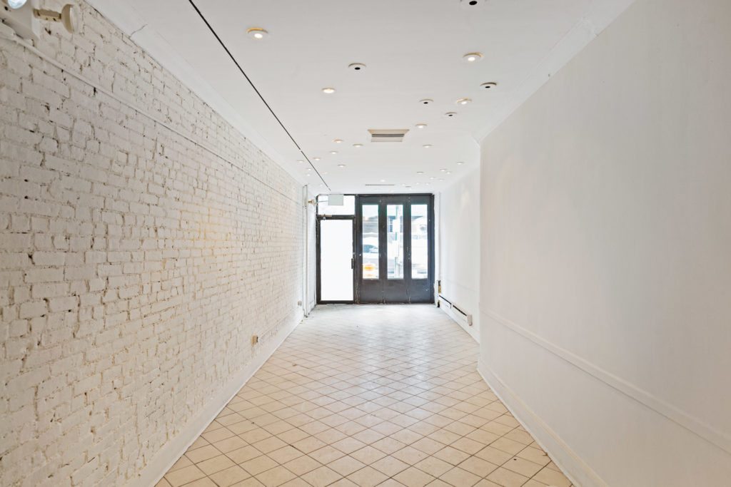 White-washed pop-up space in Upper East Side with white brick walls and storefront exterior view