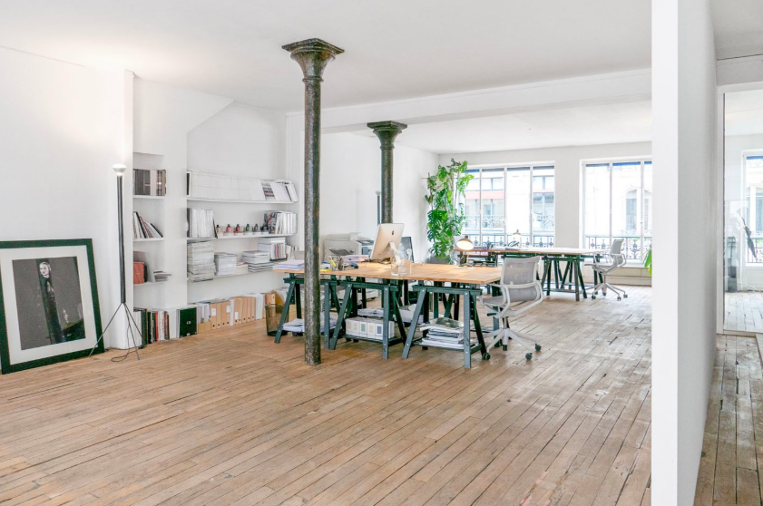 Plateau d'étage parisien avec colonnes de fonte et parquet, aménagé en espace de travail