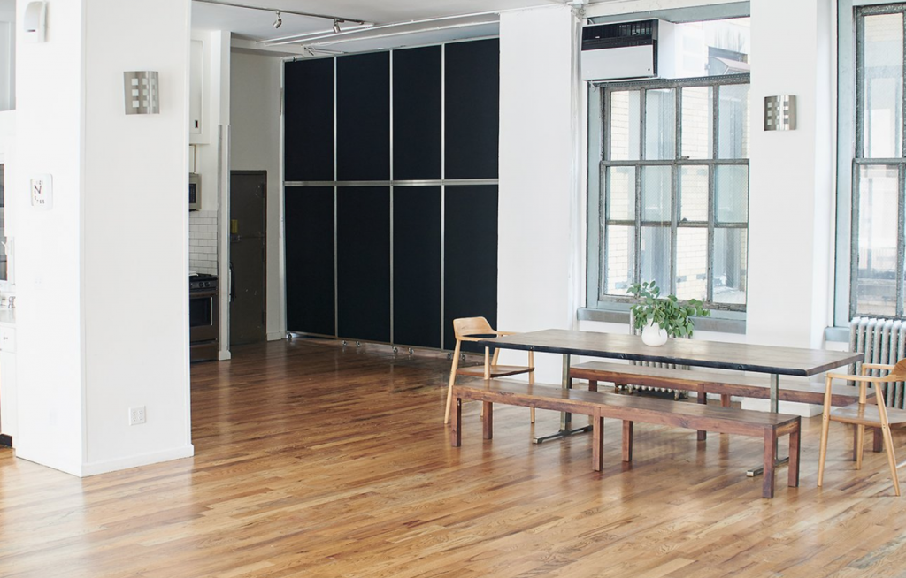 Midtown loft with timber floors, steel-framed windows and a long communal table, laid out for an event.