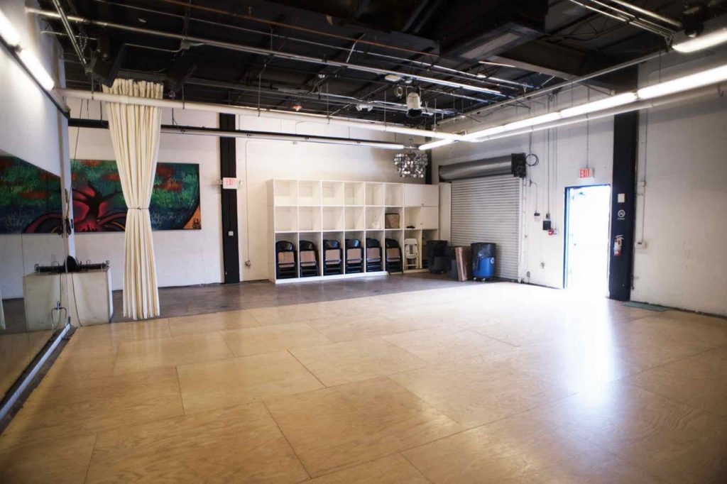 Converted Wynwood warehouse with exposed services, a roll-up door and artwork on the side wall, cleared for an event.