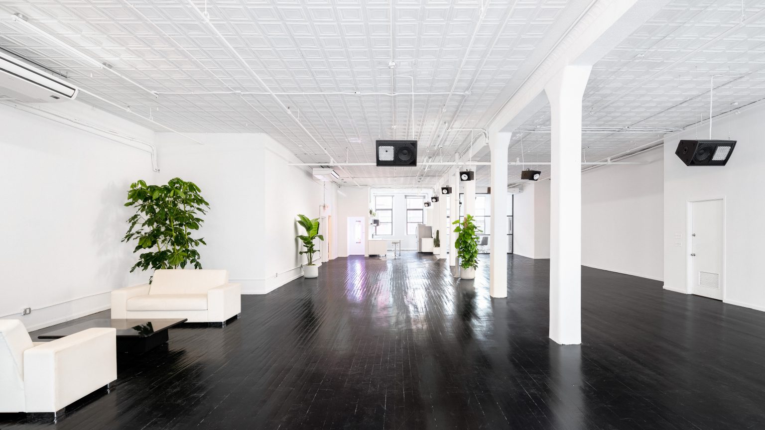 Large Tribeca loft with white columns, a pressed tin ceiling and a black timber floor, laid out as an event space.