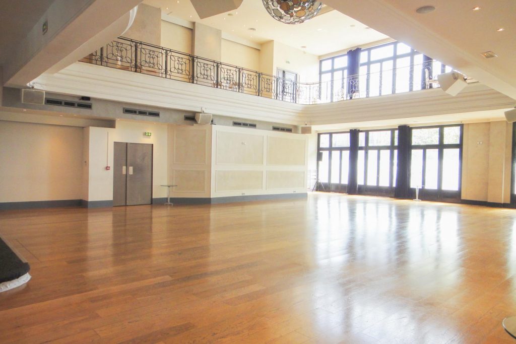 Vaste showroom moderne au parquet clair, hauts plafonds et grand espace ouvert, prêt à être aménagé en boutique éphémère.