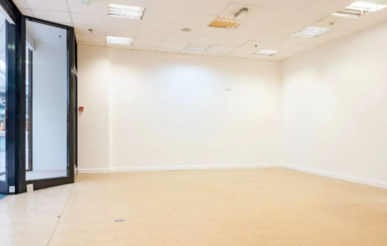 Empty retail unit in Glasgow with a black shopfront, suspended ceiling tiles and bare walls, ready for a short-term tenant to fit out.