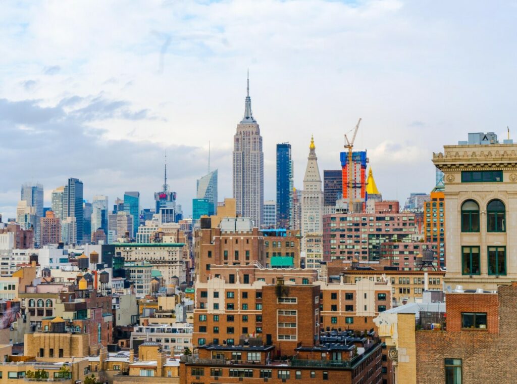 Midtown Manhattan rooftops and water towers, with the Empire State Building rising behind them.
