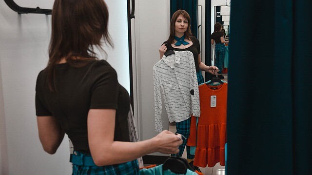 A customer trying out the new clothes by look at the mirror in the fitting room