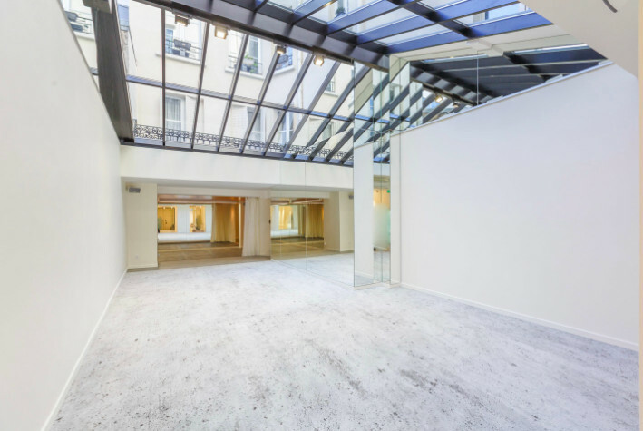 Showroom moderne blanc et lumineux avec verrière au plafond à Paris, espace ouvert prêt à emménager