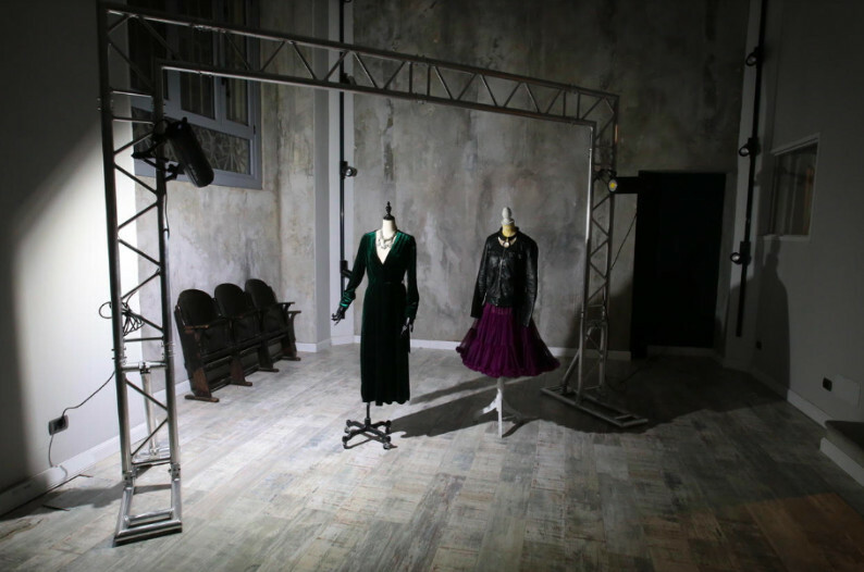 Showroom de style industriel à l'éclairage sombre et feutré, avec des mannequins vêtus de robes.