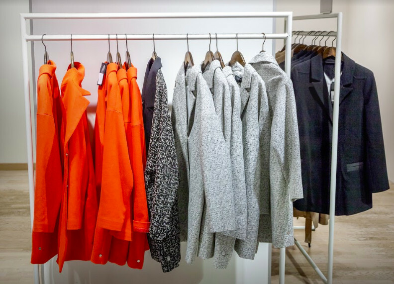 Portant présentant des vestes et des hauts rouges, gris et bleu marine dans un showroom.